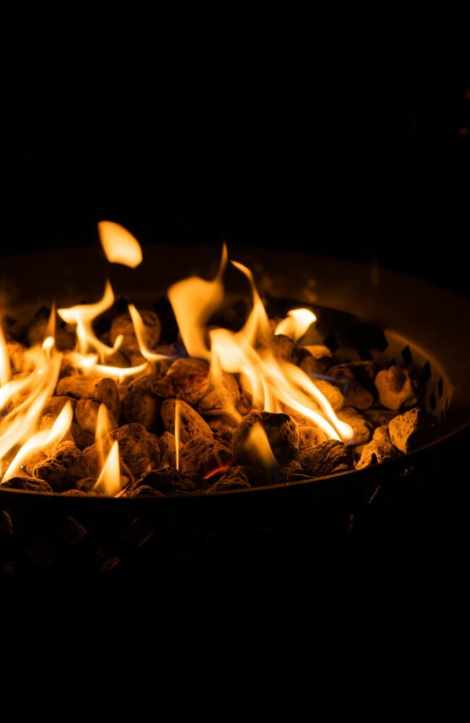 A close-up of a campfire stove illuminating the night with bright flames.