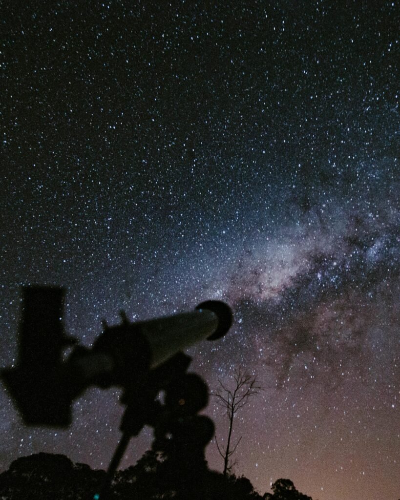 A breathtaking view of the starry night sky with a telescope silhouette capturing the beauty of the cosmos.