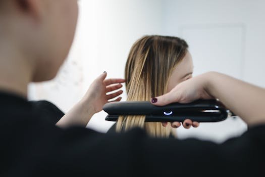 Close-up of a hairstylist using a straightening iron for sleek hairstyle indoors.