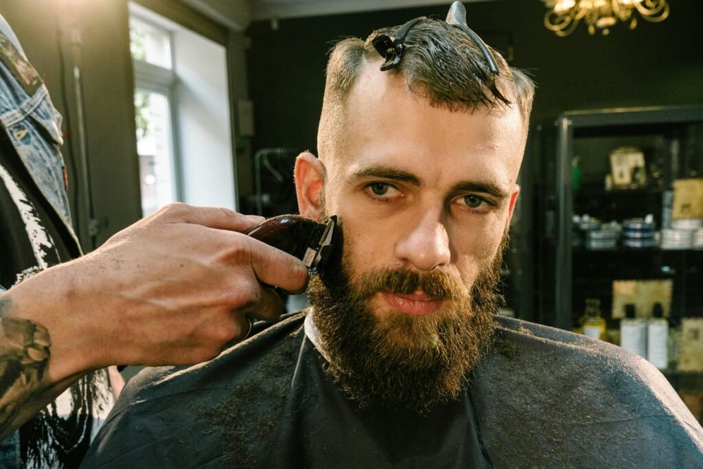 Close-up of a barber trimming a bearded man's facial hair in a stylish barber shop.