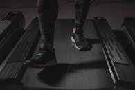 Feet running on treadmill in gym. Focus on black sneakers. Fitness and cardio exercise concept.