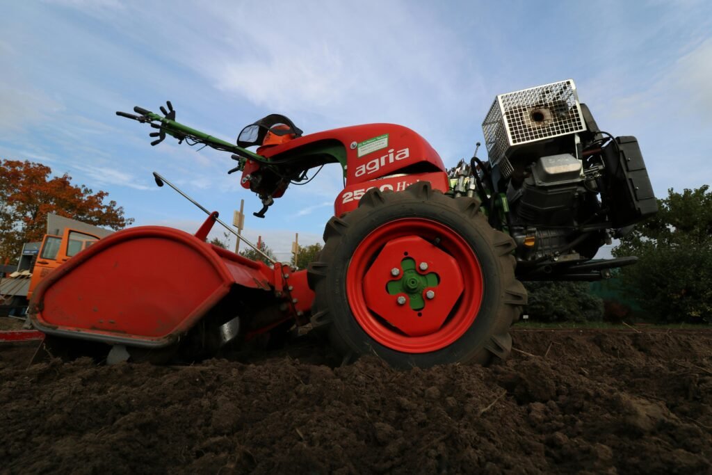 Close-up of a red two-wheeled tractor plowing a rural field, ideal for agricultural themes.