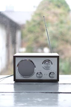 A classic radio with antenna on a wooden windowsill in a serene setting.