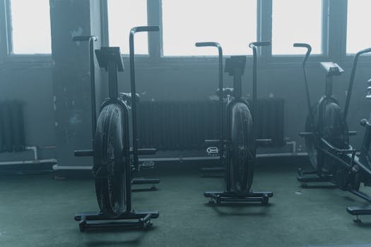 A set of exercise bikes in an empty, dimly lit gym with a muted atmosphere.