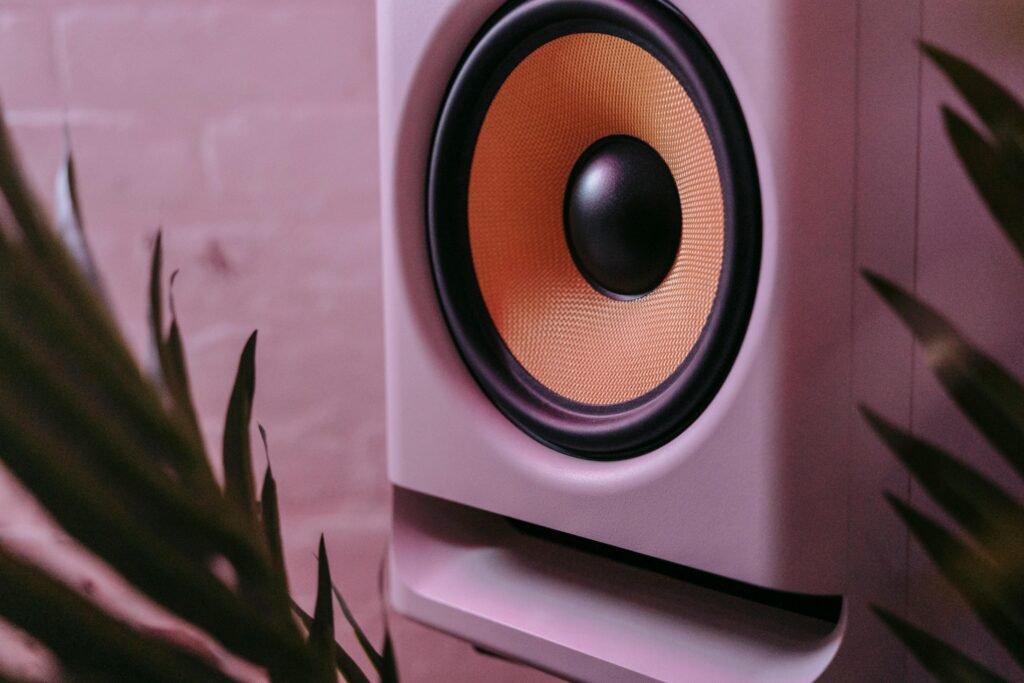 Close-up photo of a stylish subwoofer surrounded by foliage and ambient lighting.