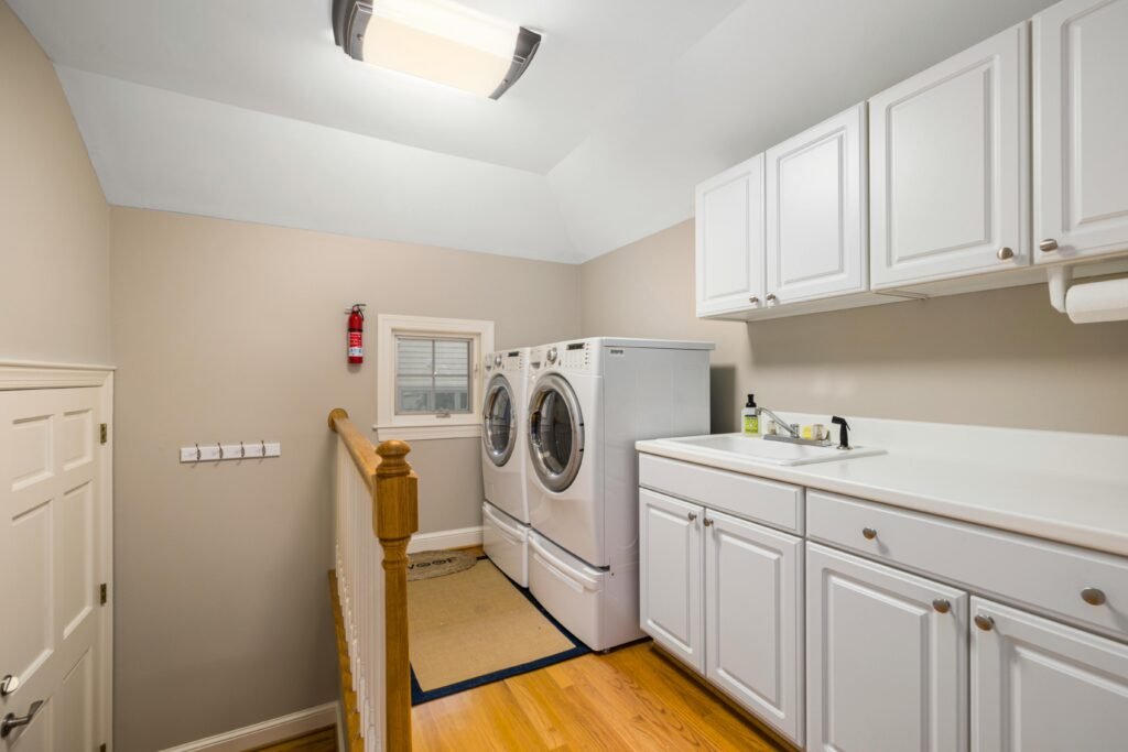 Spacious and clean laundry room featuring modern appliances and white cabinetry.